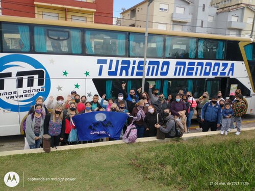 Grupo de pasajeros felices junto a micro de Ómnibus de Turismo